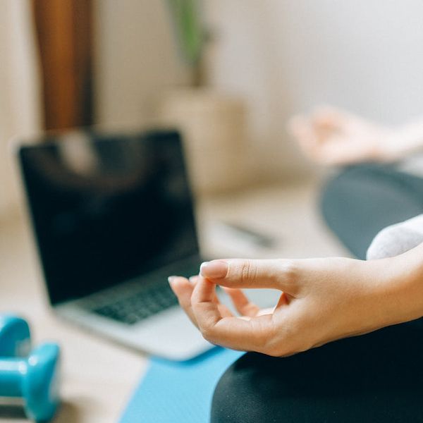 Person meditating on a yoga mat with a serene background.
